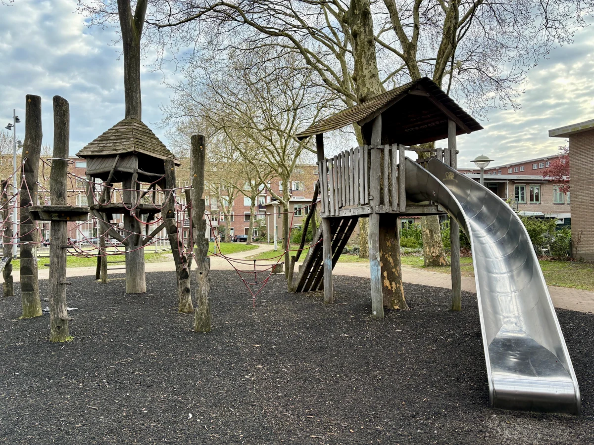 Wooden playhouses set within trees with climbing nets and slides