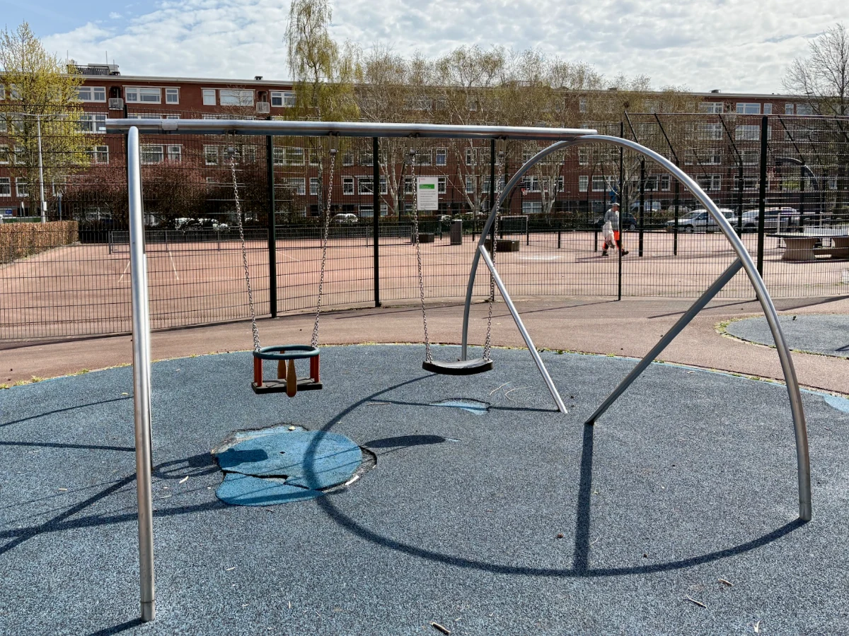 Swing set with baby swing and regular swing in front of tennis court