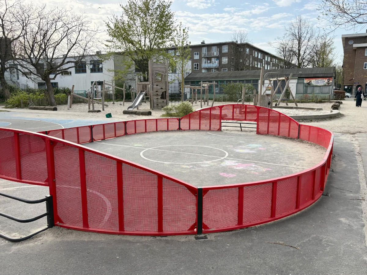 Oval-shaped mini football pitch with red metal enclosure