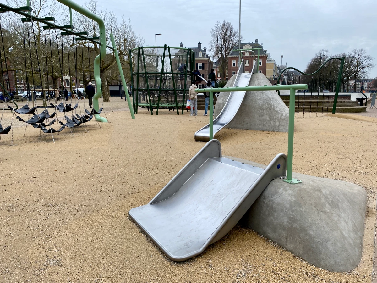 Toddler-sized metal slide, larger slide on rock, and hammock climbing structure
