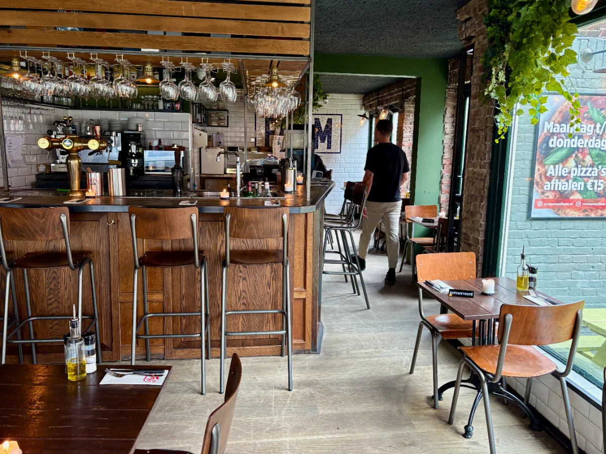 Restaurant interior with dark wood bar and stools and green walls