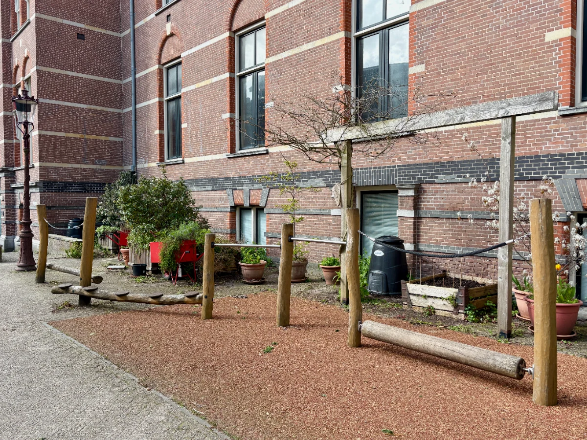 Wooden obstacle course with balance beams in front of a large brick building
