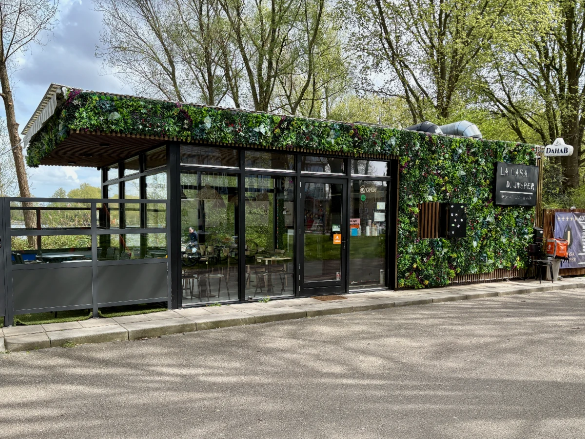 Plant-covered restaurant with glass and both indoor and outdoor seating