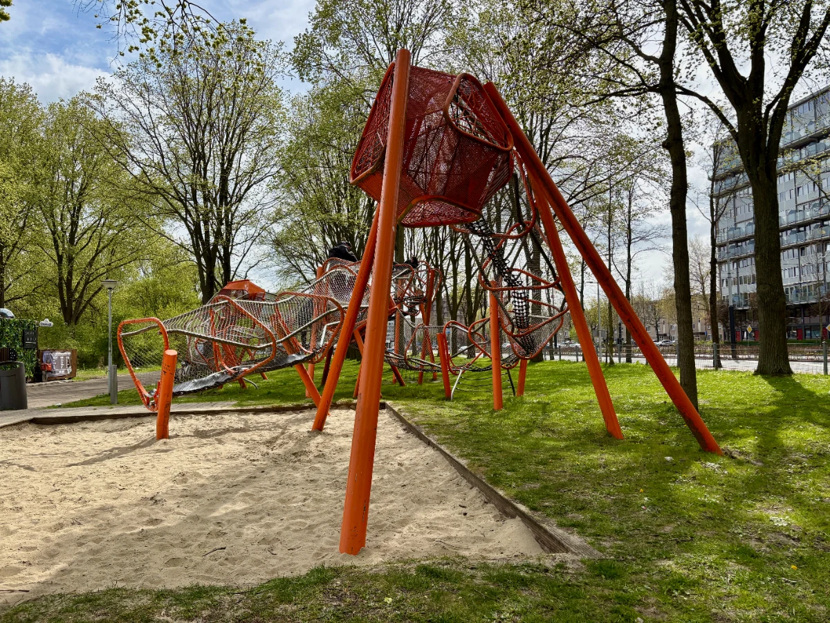 Elevated orange play garland above sand and grass in urban area