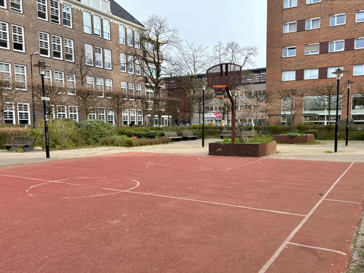 Basketball court with red-colored court set within a residential courtyard