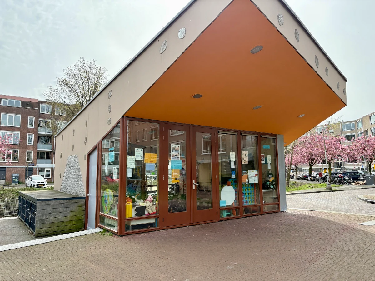 Small community center building with large overhang and big windows with toys seen inside