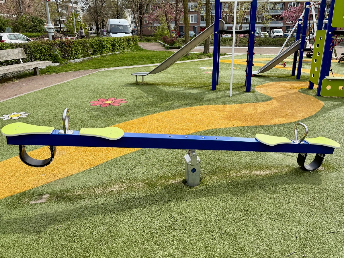 Blue and lime green seesaw on green and yellow astroturf playground